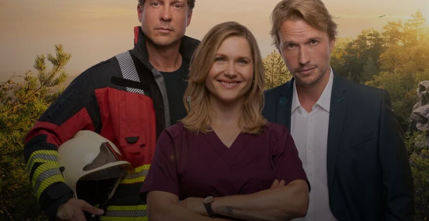 Das Bild zeigt Frieda flankiert von 2 Männern. Einer von beiden trägt eine Feuerwehruniform