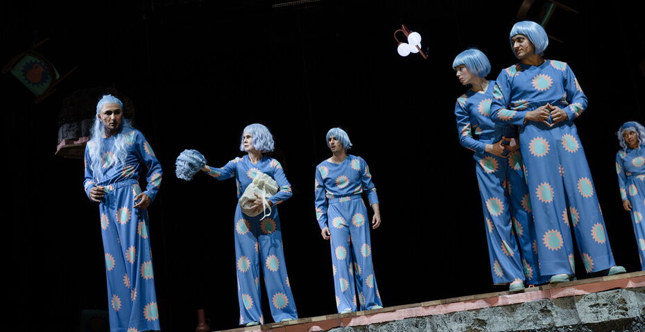 6 SChauspielende auf einer Bühne. Alle tragen blaue Perücken und Overalls